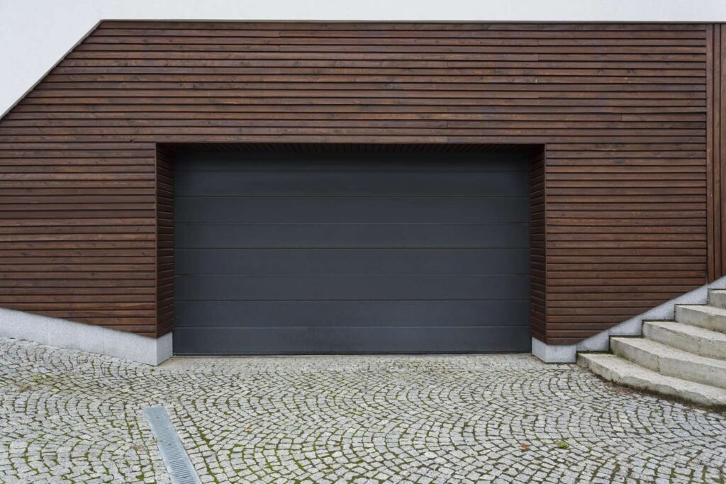 Dark flush panel garage door on a modern home with wood slat siding