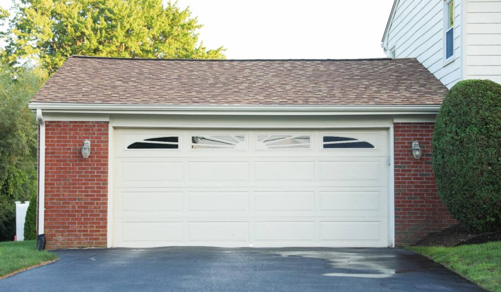 White double garage door with window panels on a brick home with asphalt driveway